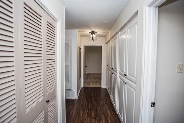 corridor featuring dark wood-type flooring and a textured ceiling