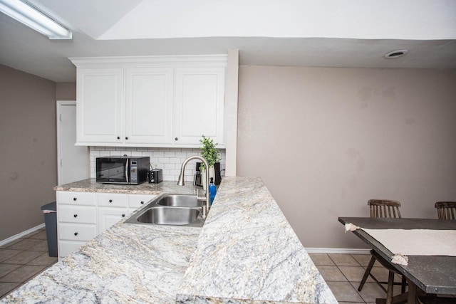 kitchen with white cabinetry, light tile patterned flooring, sink, and decorative backsplash