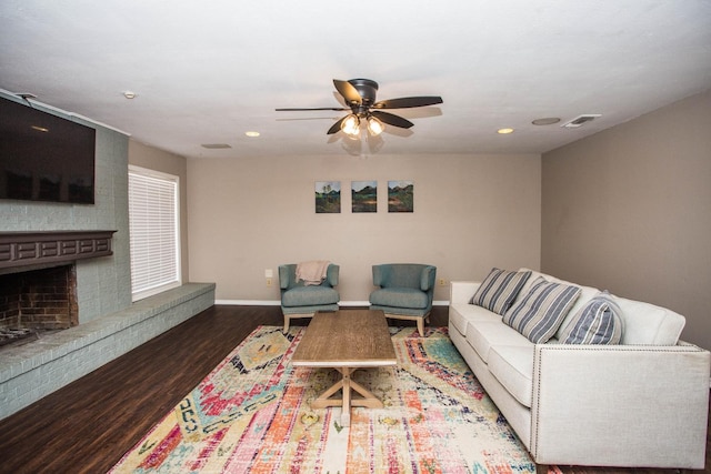 living room featuring ceiling fan, dark hardwood / wood-style floors, and a brick fireplace