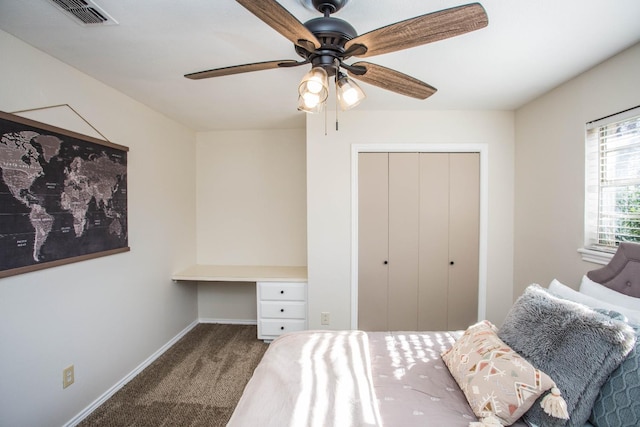 bedroom featuring built in desk, a closet, ceiling fan, and carpet