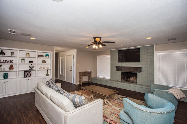 living room with dark hardwood / wood-style flooring, ceiling fan, a fireplace, and a textured ceiling