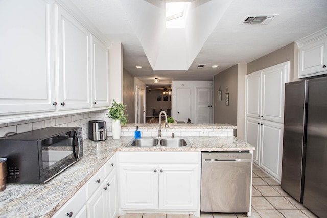 kitchen featuring sink, white cabinetry, light tile patterned floors, appliances with stainless steel finishes, and backsplash