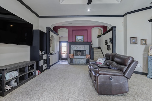 living room with crown molding, light colored carpet, ceiling fan, and a tile fireplace