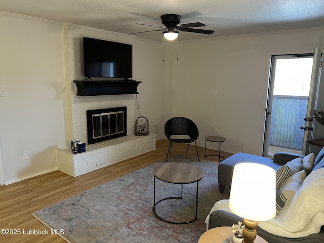8601 Memphis Dr Unit B-40, Lubbock, TX 79423 - living area with wood finished floors, a ceiling fan, crown molding, a brick fireplace, and baseboards