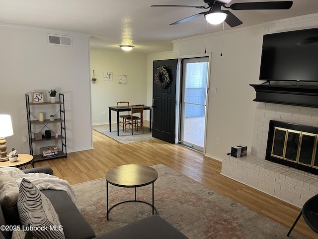 8601 Memphis Dr Unit B-40, Lubbock, TX 79423 - living room featuring light wood-type flooring, ceiling fan, ornamental molding, and a brick fireplace