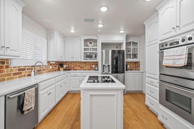 kitchen with sink, appliances with stainless steel finishes, a center island, light hardwood / wood-style floors, and white cabinets