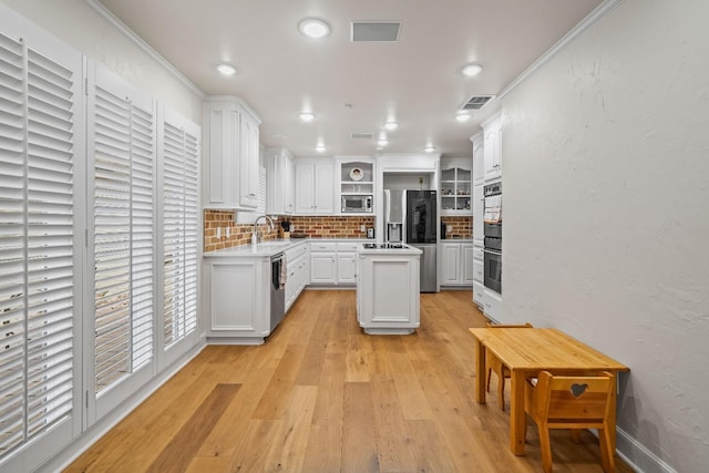 kitchen with sink, tasteful backsplash, a center island, appliances with stainless steel finishes, and white cabinets