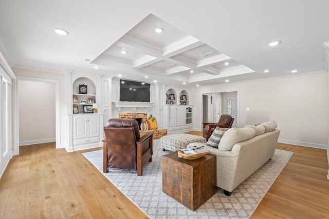 living room featuring coffered ceiling, light wood-type flooring, crown molding, and a fireplace