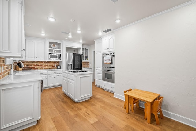 kitchen featuring sink, white cabinetry, a kitchen island, stainless steel appliances, and light hardwood / wood-style floors