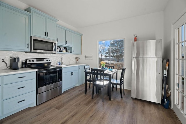 kitchen with dark hardwood / wood-style flooring, backsplash, sink, and appliances with stainless steel finishes