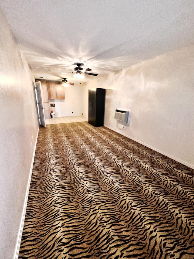 unfurnished living room with an AC wall unit, ceiling fan, a textured ceiling, and baseboards