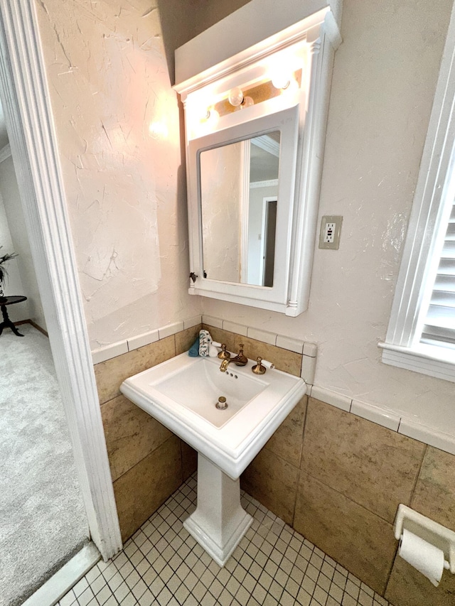 bathroom with a textured wall, wainscoting, and tile walls