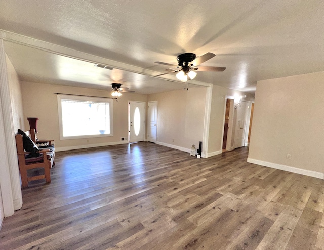 unfurnished living room featuring baseboards, a textured ceiling, visible vents, and wood finished floors