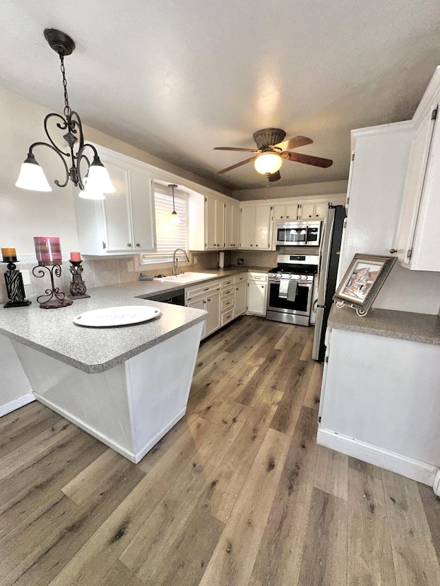 kitchen with stainless steel appliances, white cabinets, decorative light fixtures, and a peninsula