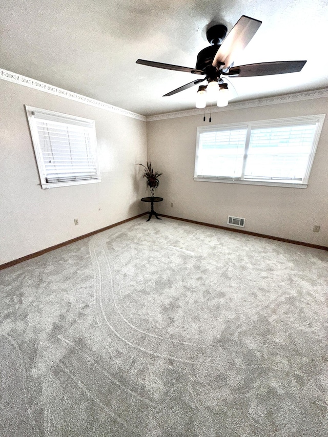 carpeted empty room with a textured ceiling, ornamental molding, visible vents, and baseboards