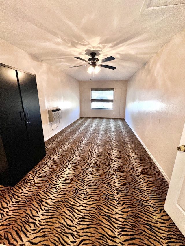 interior space with a ceiling fan, a textured ceiling, baseboards, and a wall mounted AC