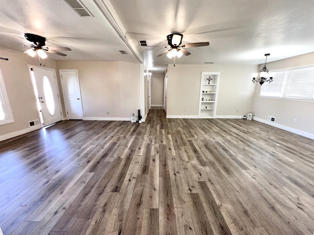 unfurnished living room featuring ceiling fan with notable chandelier, wood finished floors, and baseboards