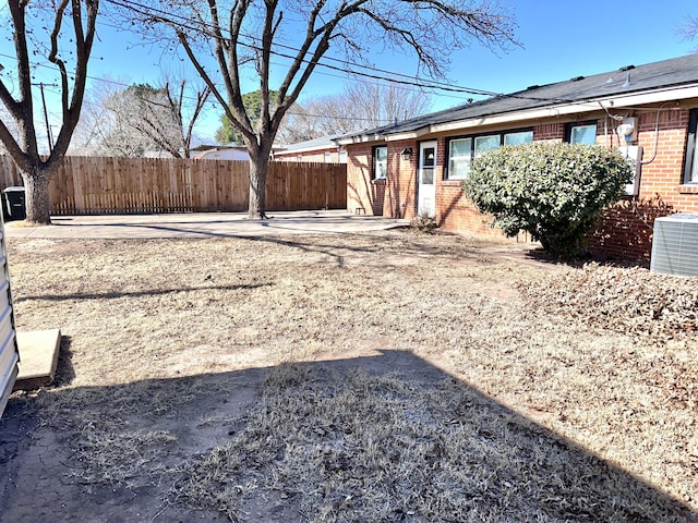 view of yard featuring a patio area, fence, and central AC unit