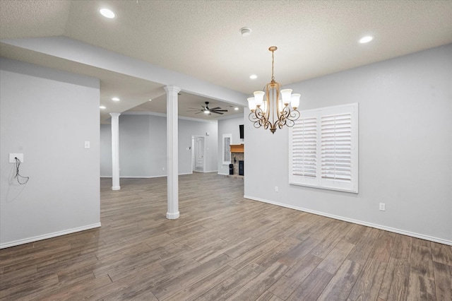 unfurnished dining area featuring hardwood / wood-style flooring, a fireplace, decorative columns, and ceiling fan with notable chandelier