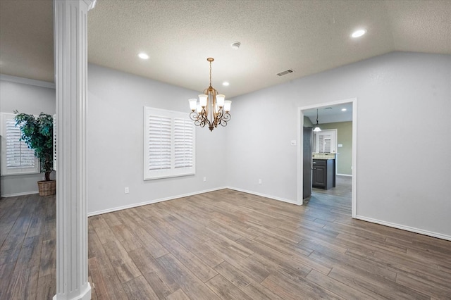 unfurnished room featuring hardwood / wood-style flooring, an inviting chandelier, and a textured ceiling