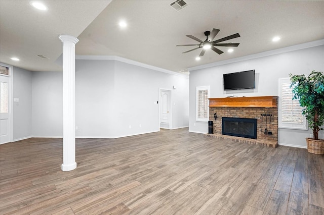 unfurnished living room with a wealth of natural light, hardwood / wood-style floors, a fireplace, decorative columns, and ceiling fan