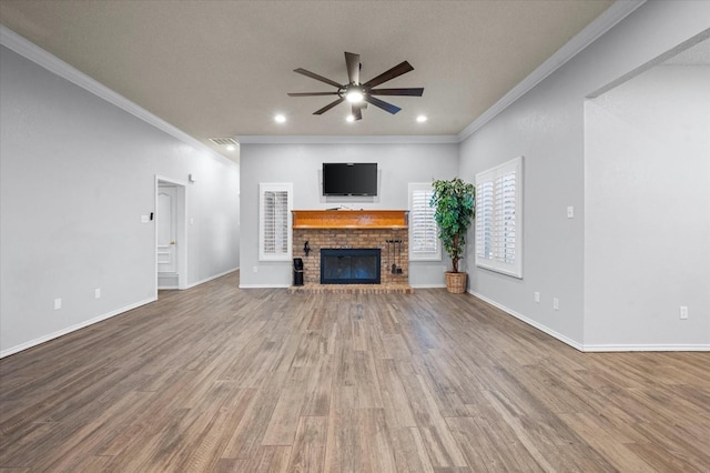 unfurnished living room featuring hardwood / wood-style flooring, crown molding, a brick fireplace, and ceiling fan