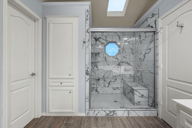 bathroom featuring a skylight, an enclosed shower, and hardwood / wood-style floors