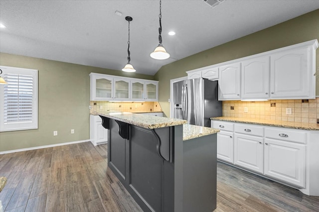 kitchen with white cabinetry, stainless steel fridge with ice dispenser, light stone counters, and decorative light fixtures