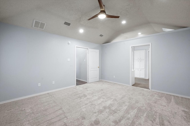 unfurnished bedroom with connected bathroom, vaulted ceiling, a textured ceiling, ceiling fan, and carpet