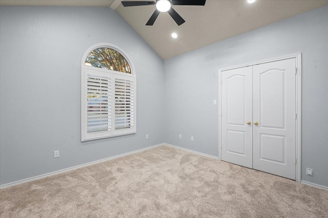 empty room with ceiling fan, light colored carpet, and vaulted ceiling