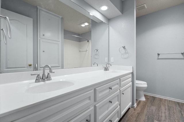 bathroom featuring hardwood / wood-style flooring, vanity, toilet, and walk in shower