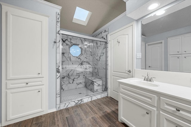 bathroom featuring hardwood / wood-style floors, a skylight, vanity, an enclosed shower, and a textured ceiling