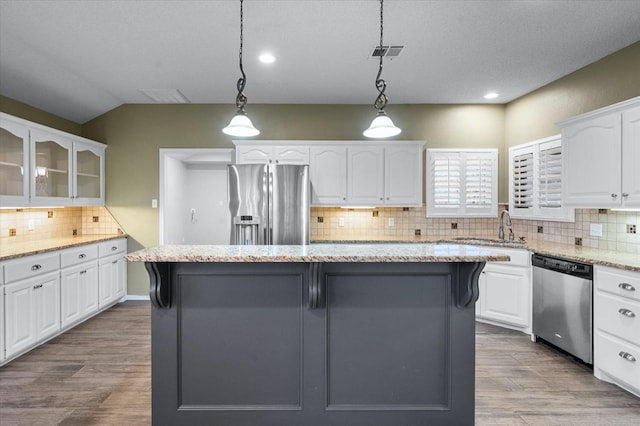 kitchen with white cabinetry, hanging light fixtures, stainless steel appliances, and a kitchen island