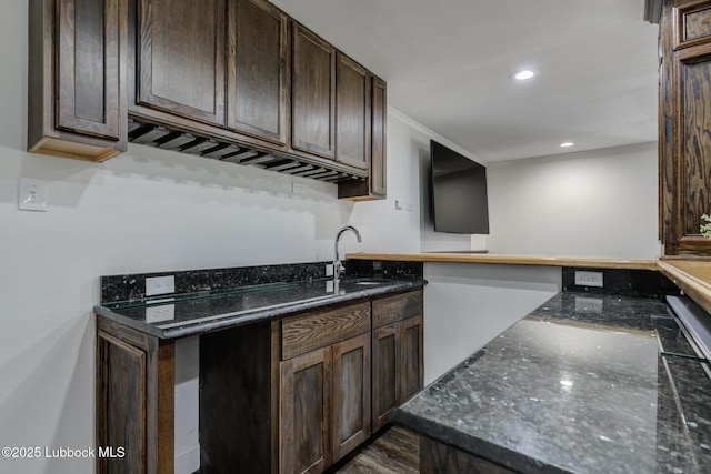 4517 9th St, Lubbock, TX 79416 - kitchen with a sink, dark brown cabinets, dark stone countertops, crown molding, and recessed lighting