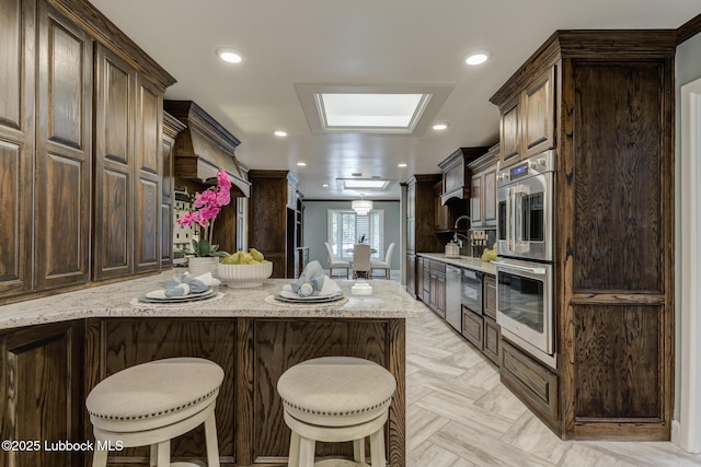 4517 9th St, Lubbock, TX 79416 - kitchen featuring stainless steel appliances, a kitchen breakfast bar, dark brown cabinetry, and recessed lighting