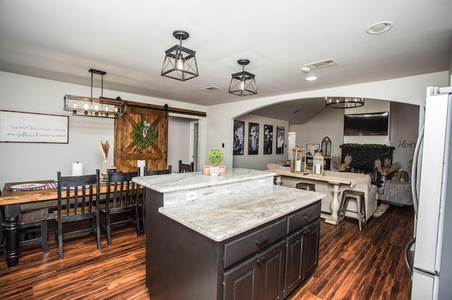 2911 111th St, Lubbock, TX 79423 - kitchen featuring freestanding refrigerator, dark wood-type flooring, a kitchen island, and a barn door