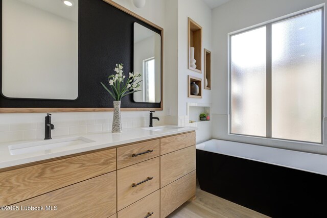 3817 128th St, Lubbock, TX 79423 - bathroom featuring double vanity, healthy amount of natural light, a garden tub, and wood finished floors