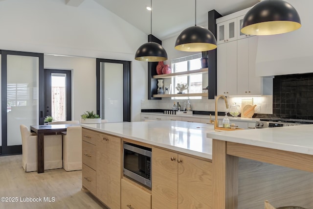 3817 128th St, Lubbock, TX 79423 - kitchen with stainless steel microwave, backsplash, healthy amount of natural light, light countertops, and lofted ceiling