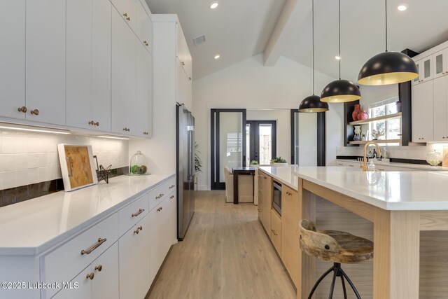 3817 128th St, Lubbock, TX 79423 - kitchen featuring stainless steel appliances, decorative backsplash, light wood finished floors, light countertops, and a kitchen island with sink