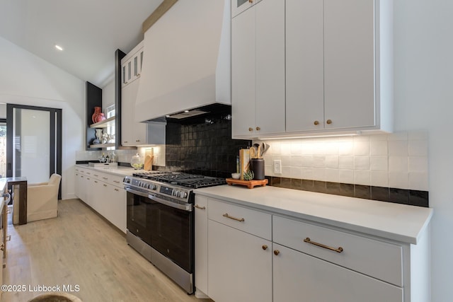 3817 128th St, Lubbock, TX 79423 - kitchen featuring stainless steel gas range oven, custom exhaust hood, light wood finished floors, white cabinetry, and vaulted ceiling