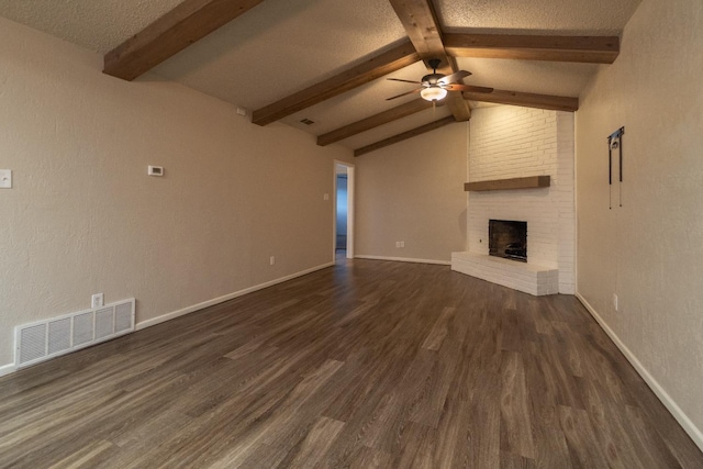 unfurnished living room featuring lofted ceiling with beams, ceiling fan, a brick fireplace, dark wood-type flooring, and a textured ceiling