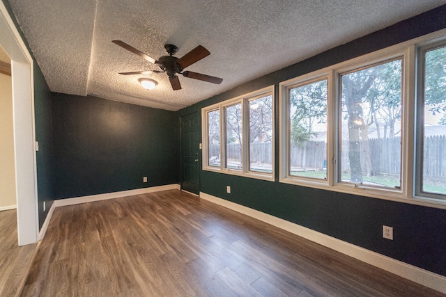 empty room featuring ceiling fan, plenty of natural light, hardwood / wood-style floors, and a textured ceiling