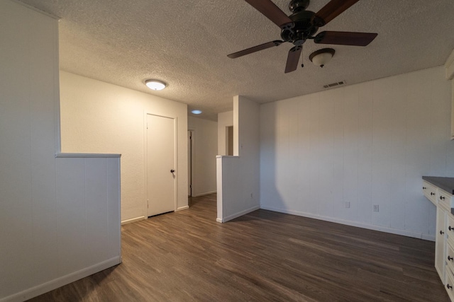 spare room featuring dark wood-type flooring, ceiling fan, and a textured ceiling