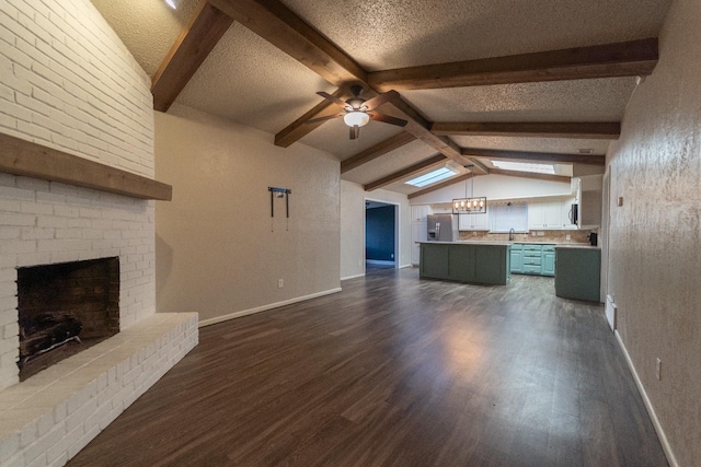 unfurnished living room with ceiling fan, dark hardwood / wood-style floors, a fireplace, lofted ceiling with beams, and a textured ceiling