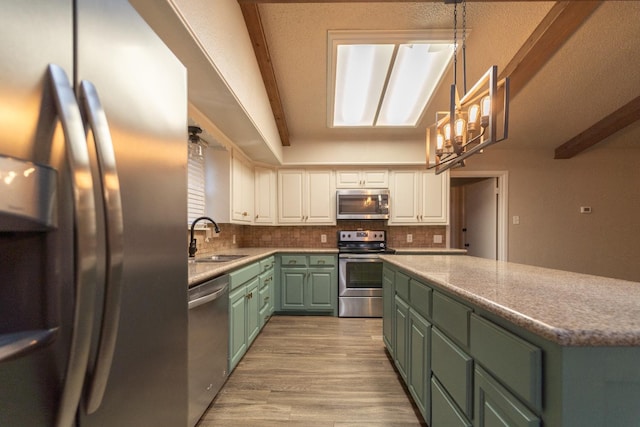 kitchen with sink, appliances with stainless steel finishes, pendant lighting, decorative backsplash, and white cabinets