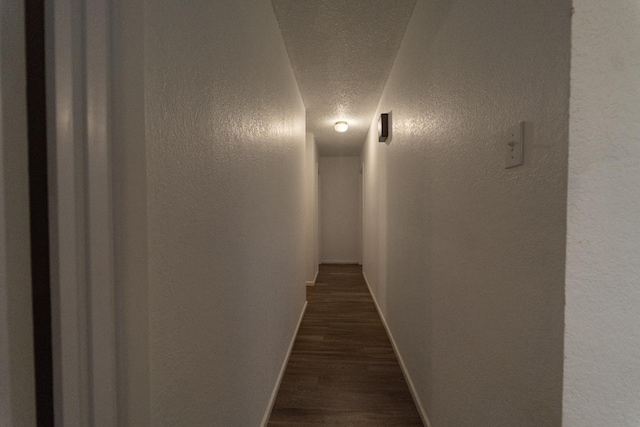 hallway with dark hardwood / wood-style flooring and a textured ceiling