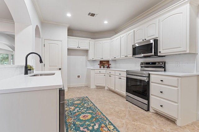 kitchen with sink, crown molding, appliances with stainless steel finishes, white cabinets, and decorative backsplash