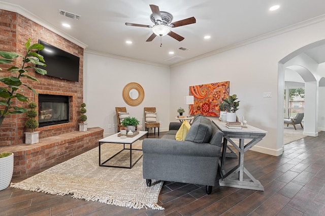 living room featuring a fireplace, ornamental molding, and ceiling fan