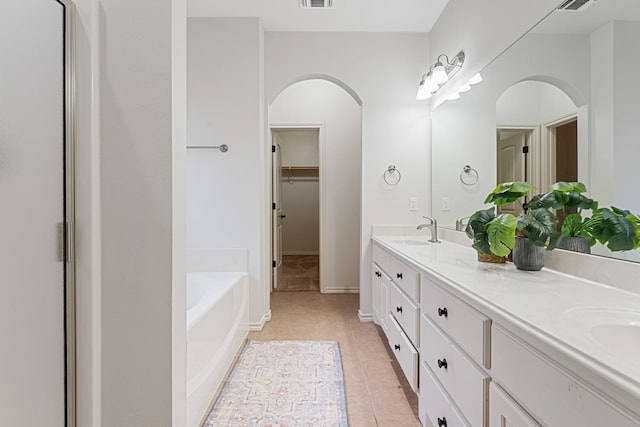 bathroom with tile patterned floors, vanity, and a washtub