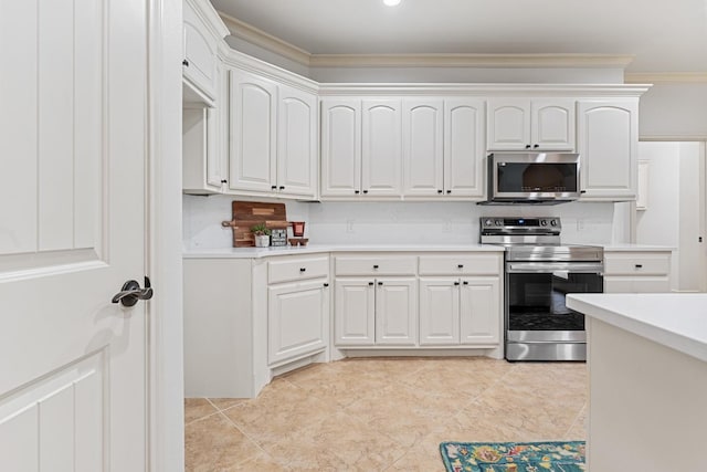 kitchen with ornamental molding, appliances with stainless steel finishes, and white cabinets